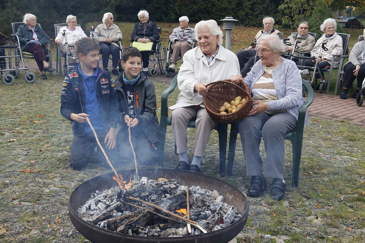 Senioren und Jugendliche beim Kartoffelfeuer