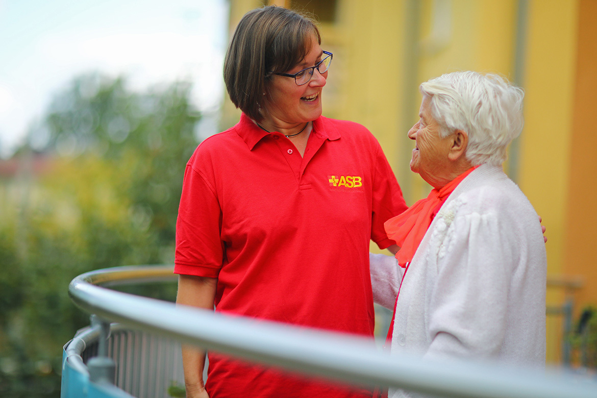 Eine Pflegekraft spricht mit einer Seniorin