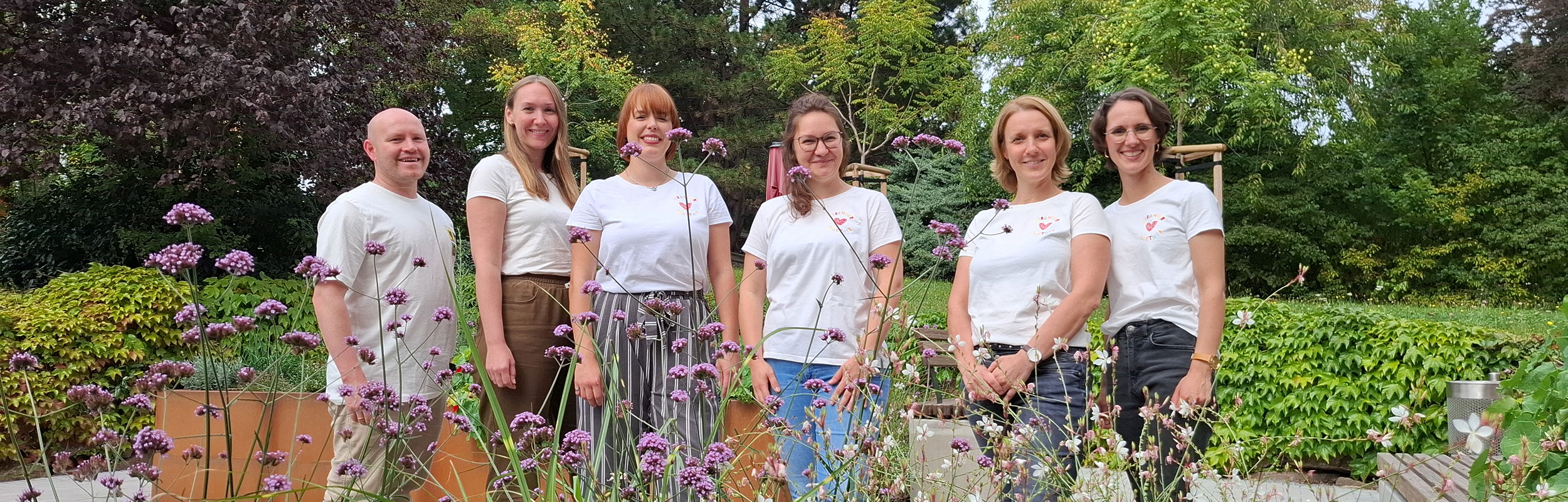 Die Kolleginnen und Kollegen des Förder- und Therapiezentrums Dresden stehen im Grünen und lächeln. 