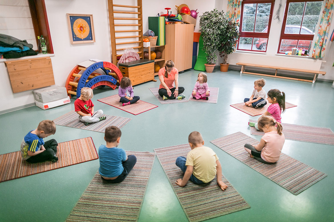 Kinder und Erzieherin entspannen auf Matten